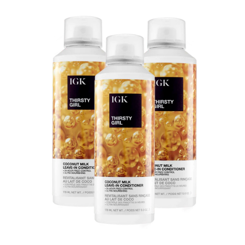 Three bottles of IGK Thirsty Girl Coconut Milk Leave-In Conditioner with gold bubbles on the label.